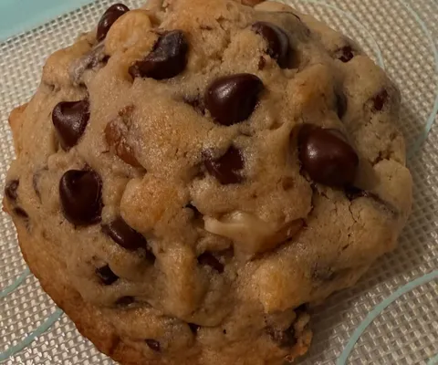 Thick NYC-style chocolate chip walnut cookie with glossy chocolate chips and flaky sea salt