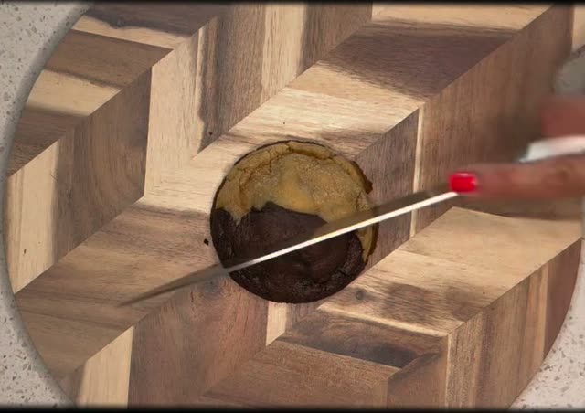 A knife slicing through a half-chocolate half-classic stuffed cookie on a cutting board